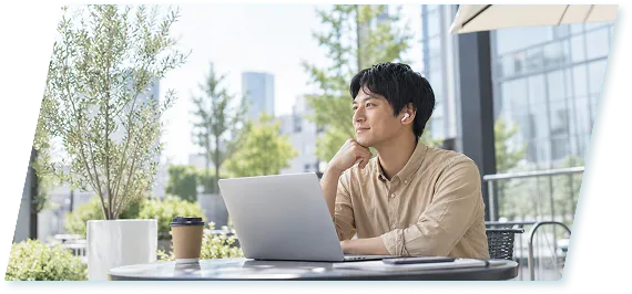 屋外のカフェでノートパソコンを使って働く男性